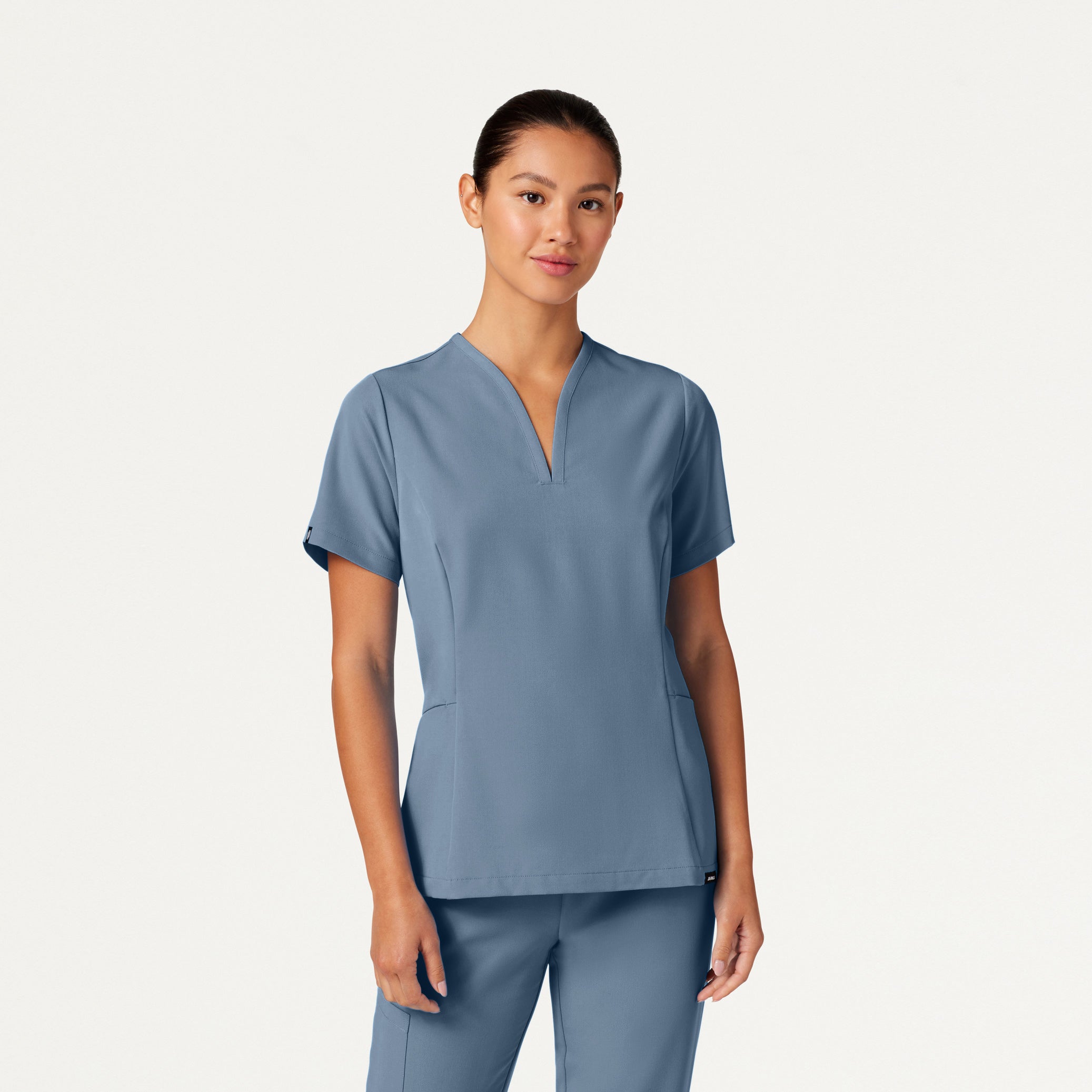 Woman wearing a blue scrub top and pants on a white background
