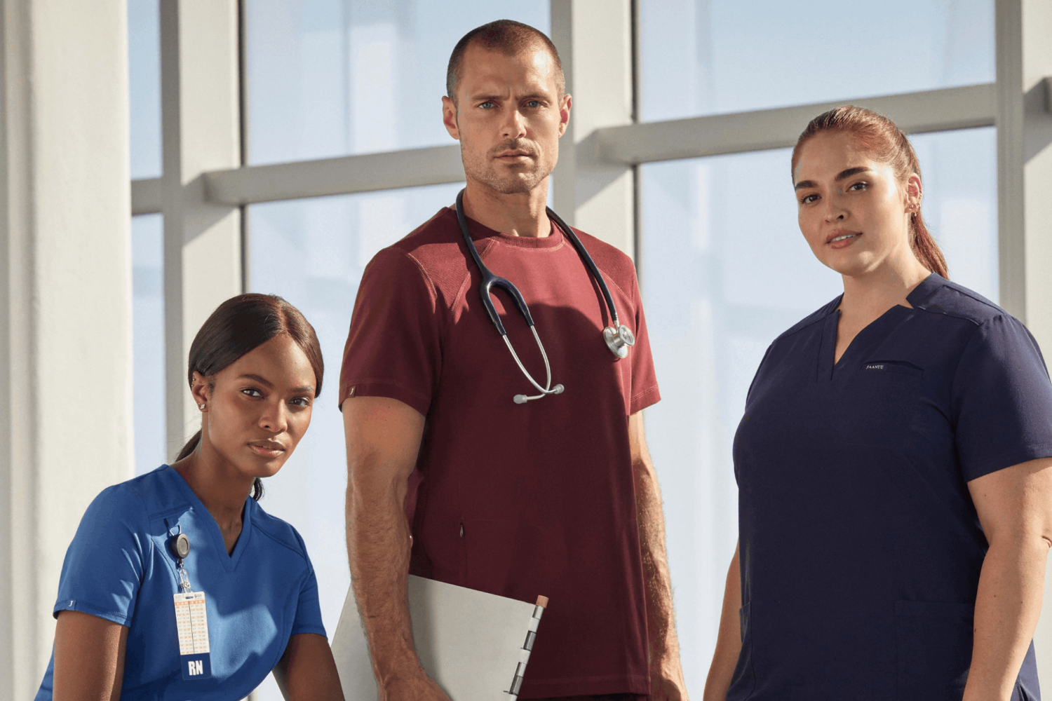 Man in between two women wearing different color scrubs