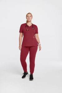 Woman wearing pocket rose trim top plus size scrubs in wine