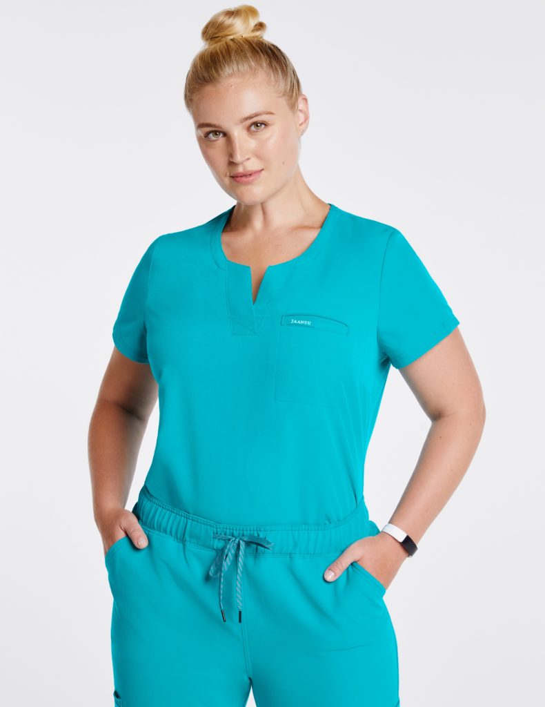 Plus nurse wearing relaxed pocket tuck in top teal scrubs