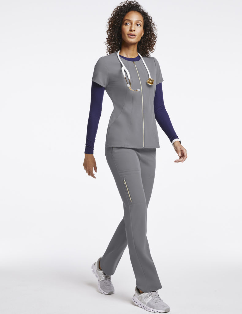 Nurse wearing gold zip flare pant scrubs in gray