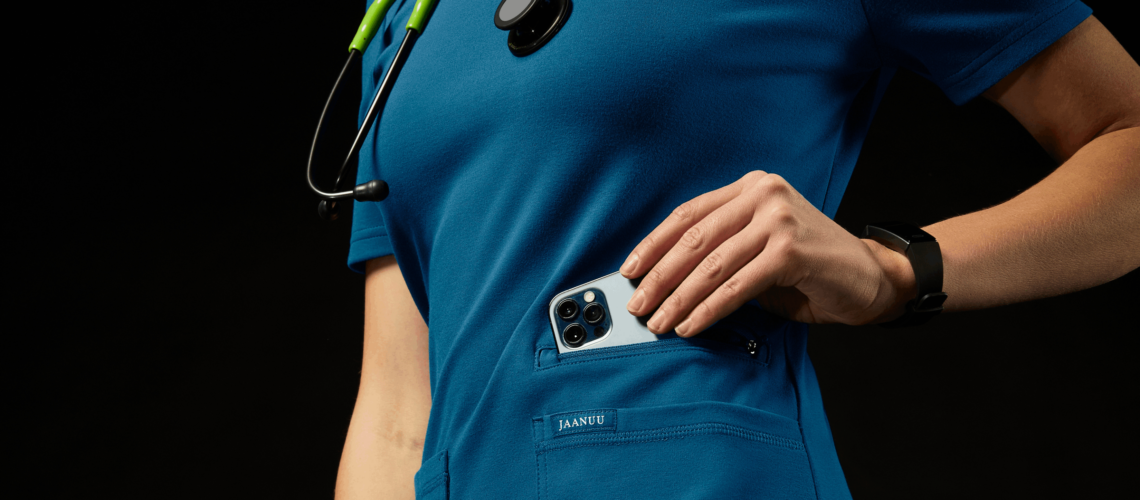 health professional in blue scrubs with wrist device and phone in hand