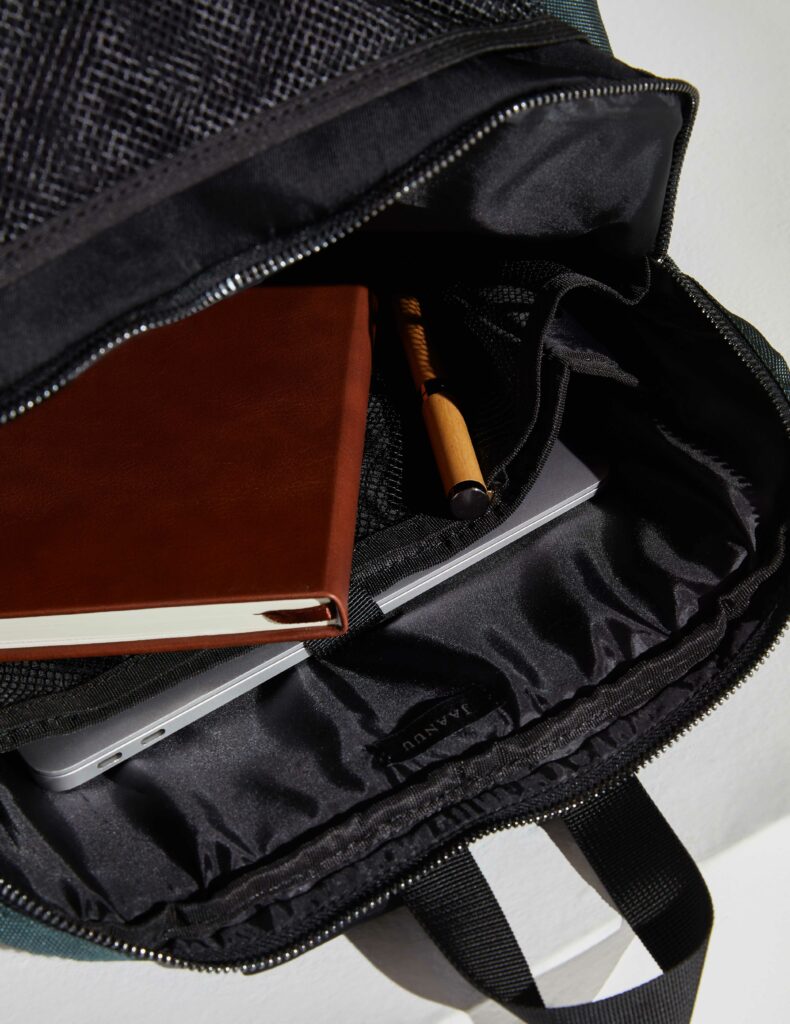 Black backpack with a notebook, a computer, and a pen inside