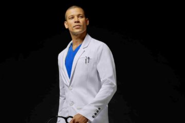Doctor-with-white-coat-standing-in-front-of-black-background