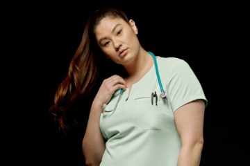 female-nurse-wearing-light-green-uniform-in-front-of-black-background