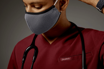 Male nurse wearing gray mask and red scrub with stethoscope hanging on his neck