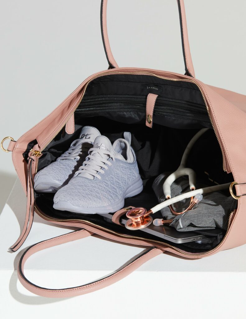 pink handbag with gray running shoes, computer, and white stethoscope inside