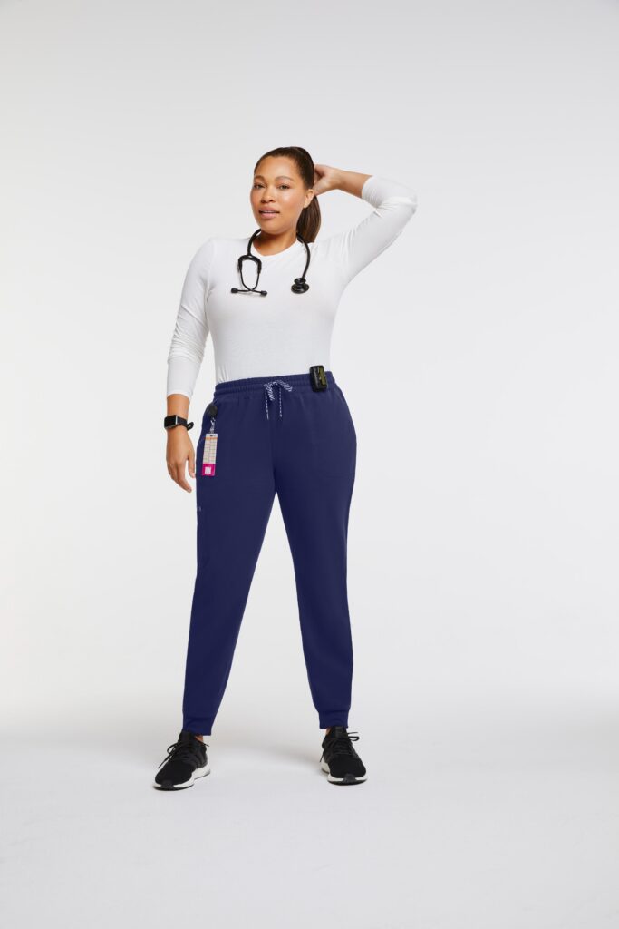 Plus size female oncology nurse wearing white top, navy blue jogger pants and back stethoscope