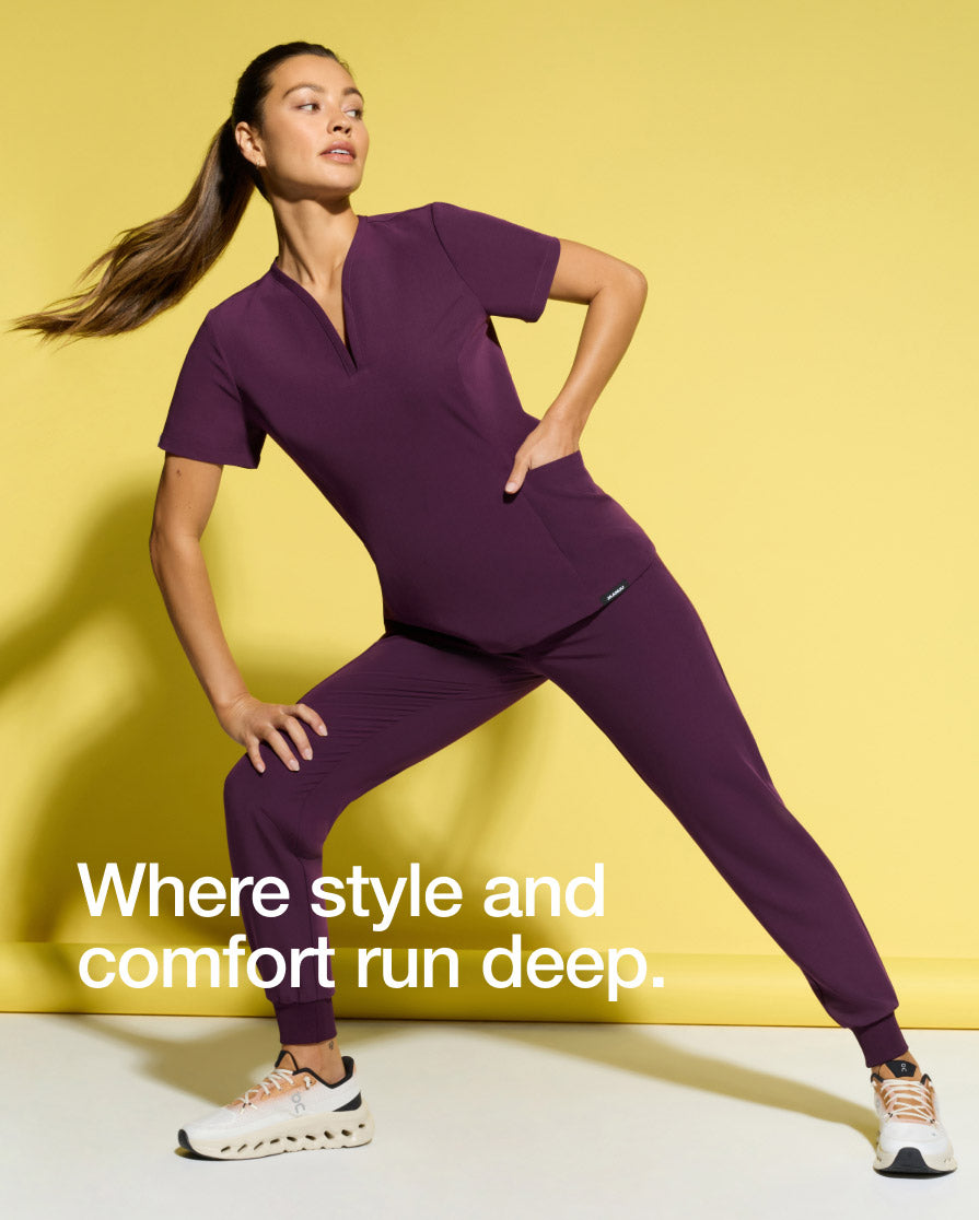 Image of woman wearing JAANUU scrubs in Deep Eggplant. Image has text, "Where style and comfort run deep.".