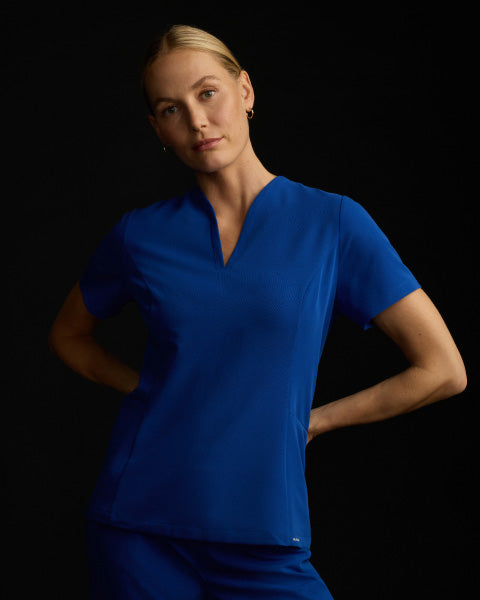 A woman wearing JAANUU scrubs in Galaxy color. - Women Nav Tile