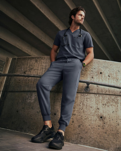 A man wearing a JAANUU scrub set in Carbon Gray color. - Men Nav Tile