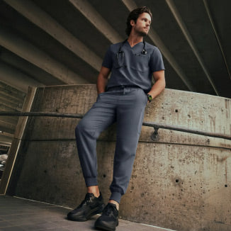 A man wearing a JAANUU scrub set in Carbon Gray color. - Men Nav Tile