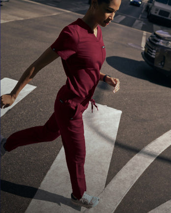 A women wearing a JAANUU scrub set in Burgundy color. - Women Nav Tile