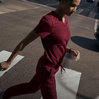 A women wearing a JAANUU scrub set in Burgundy color. - Women Nav Tile