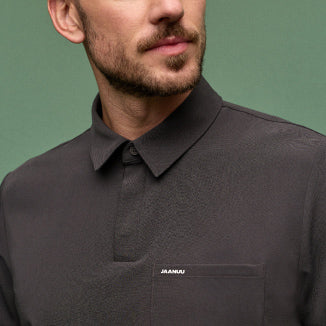 A man wearing a JAANUU polo scrub top in Charcoal color. - Men Nav Tile