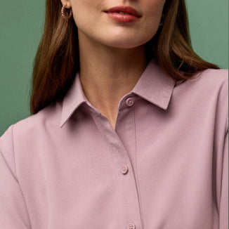 A women wearing a JAANUU collared scrub top. - Women Nav Tile