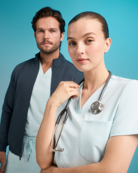 A women and a man wearing a JAANUU scrubs in color Sky Blue. - Men Nav Tile