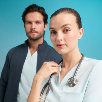 A women and a man wearing a JAANUU scrubs in color Sky Blue. - Men Nav Tile