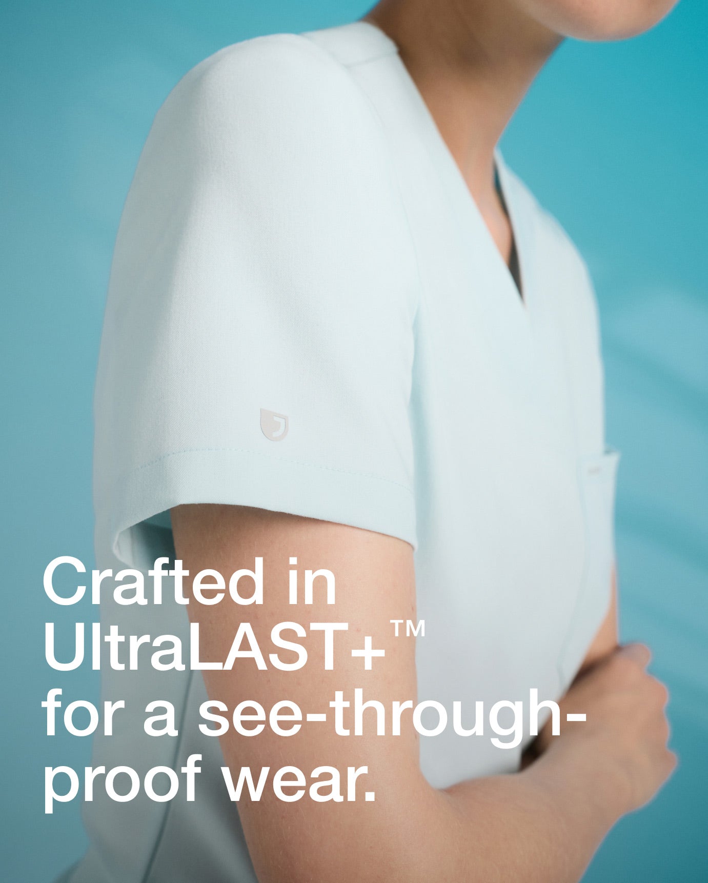 Image of a woman wearing JAANUU in color Sky Blue scrubs. "Image has text, "Crafted in UltraLAST+ for a see-through-proof wear.".