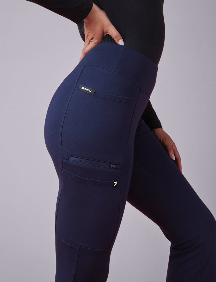 A women wearing Midnight Blue scrub pant and a Black underscrub with the JAANUU brand logo on a gray background