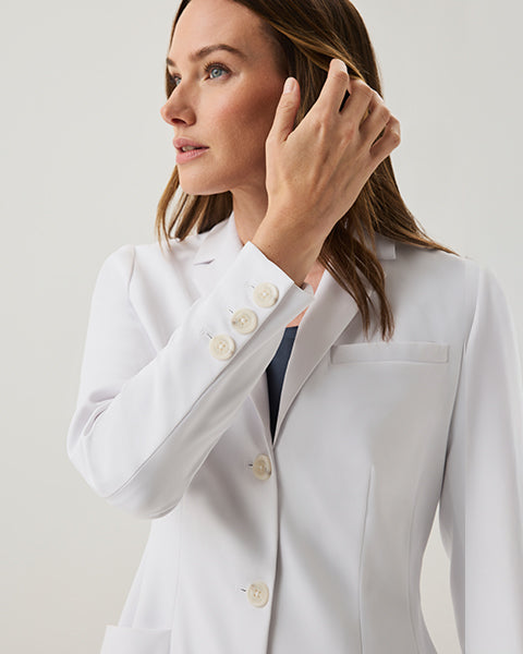 Close-up of a woman in a white Jaanuu lab coat highlighting the button detail at the collar - Women Nav Tile
