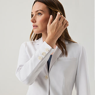 Close-up of a woman in a white Jaanuu lab coat highlighting the button detail at the collar - Women Nav Tile