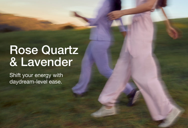 Two women in motion-blurred shot running through a grassy field, one in lavender and one in rose quartz Jaanuu scrubs, with text 'Rose Quartz & Lavender' and 'Shift your energy with daydream-level ease.'