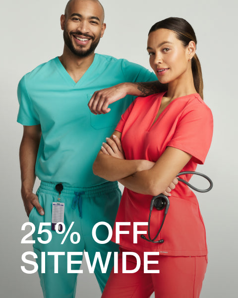 Man wearing a surf teal Jaanuu scrub top and woman wearing a coral Jaanuu scrub top standing together, with text '25% Off Sitewide' - Women Nav Tile