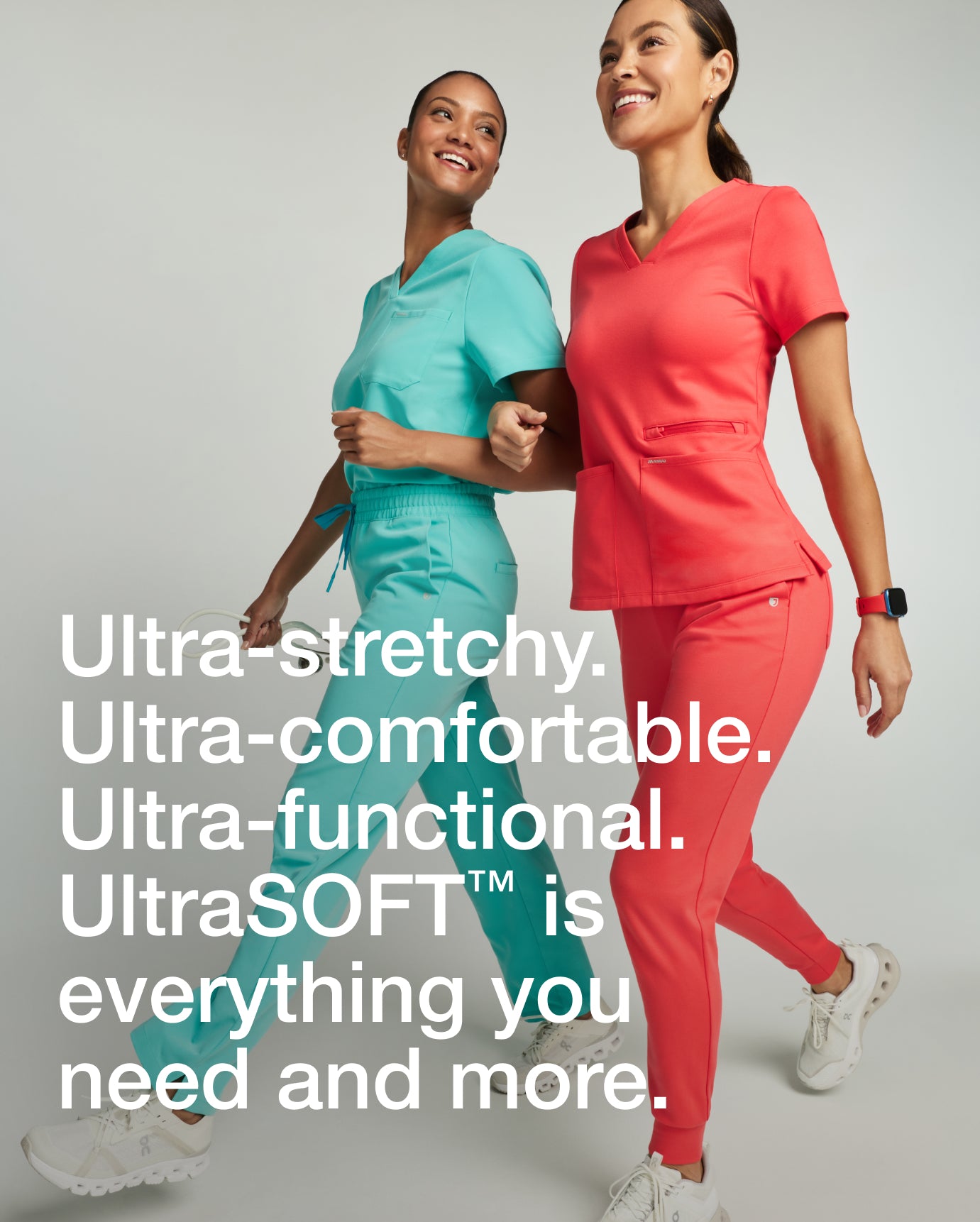 Two women walking together in surf teal and coral Jaanuu scrubs, with text 'Ultra-stretchy. Ultra-comfortable. Ultra-functional. UltraSOFT™ is everything you need and more.'