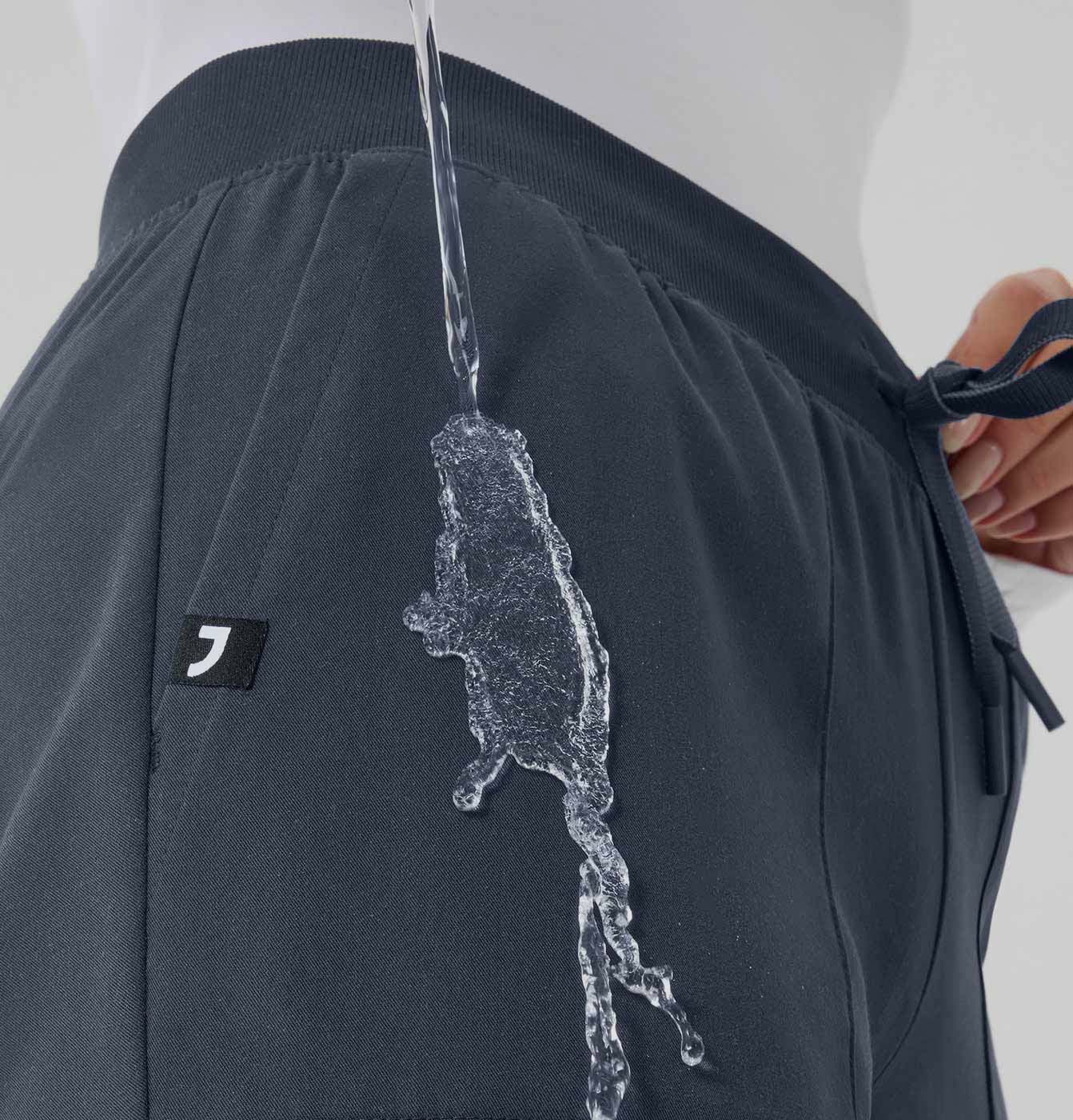 Image of water being poured on scrub pants with PFC-free water repellency. The water is rolling off the scrub pants.