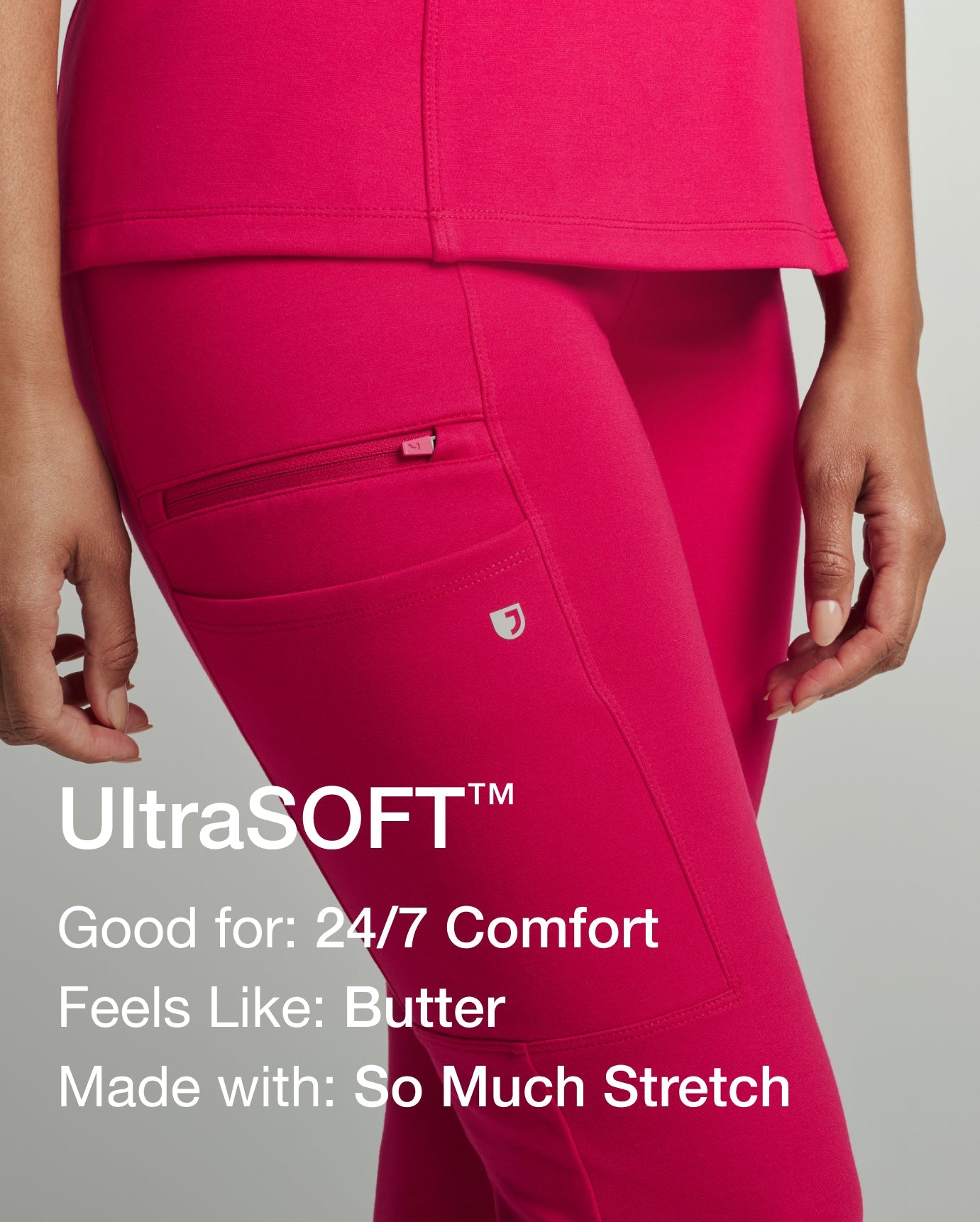 Woman shown from the waist down in hot-pink Sangria scrubs, hand resting near the thigh cargo pocket with the Jaanuu logo. Text reads: UltraSOFT™. Good for: 24/7 Comfort. Feels Like: Butter. Made with: So Much Stretch.