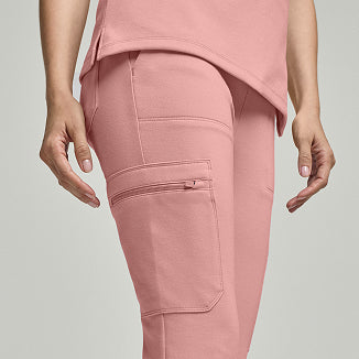 Woman wearing dusty rose Jaanuu scrub joggers with a side cargo pocket. - Women Nav Tile