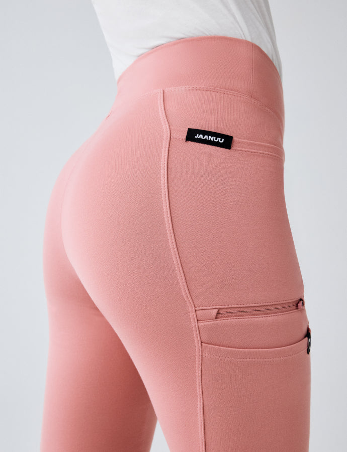Close-up of pink UltraSOFT scrub pants with a zippered side pocket and JAANUU waistband label