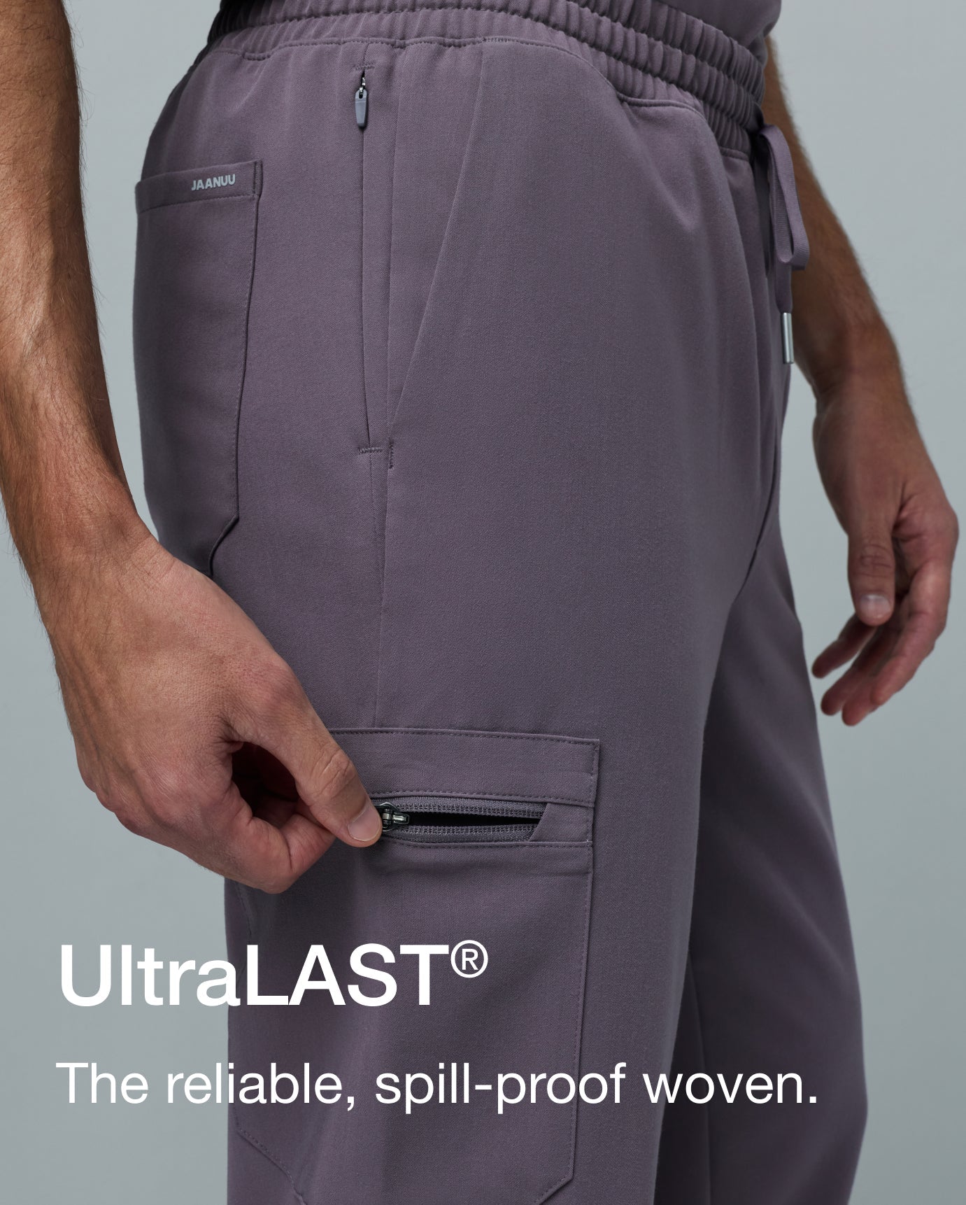 Close-up of a man in warm gray Jaanuu Titanium UltraLAST scrub pants unzipping the cargo pocket. Text on the image reads: "UltraLAST®. The reliable, spill-proof woven."