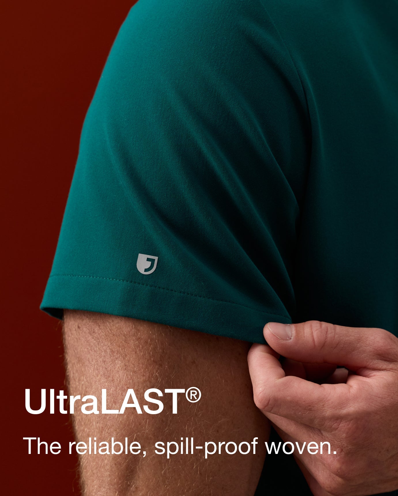 Close view of a man pinching the short sleeve of his Midnight Green scrub top. Text on image reads: "UltraLAST®. The reliable, spill-proof woven."