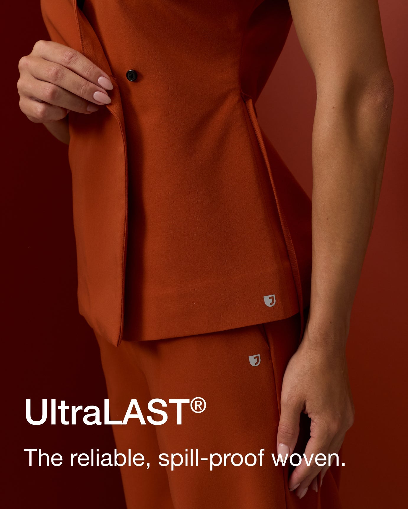 A woman in a Sienna scrub vest and pant adjusts the vest closure, shown in close detail. Text on image reads: "UltraLAST®. The reliable, spill-proof woven."