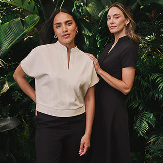 Two women standing. One is wearing fashionable scrubs and the other is wearing a scrub dress. - Women Nav Tile