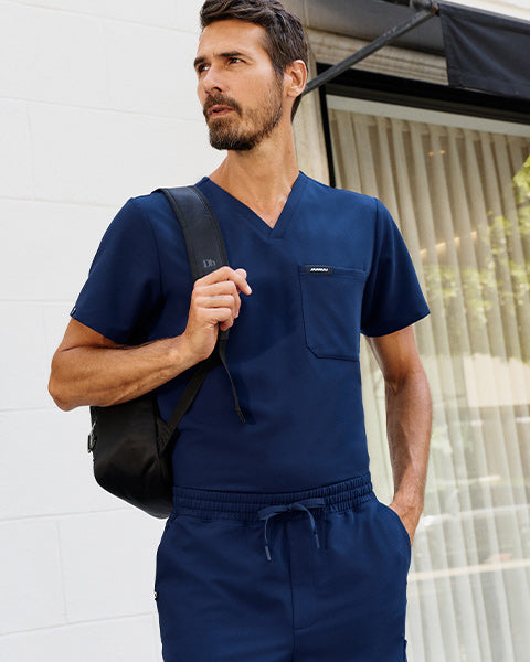 Man wearing slim scrubs with a backpack. - Men Nav Tile