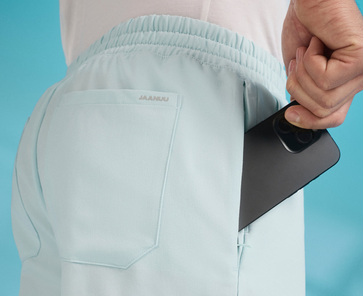 Close-up of a phone going into the back pocket of light blue UltraLAST+™ scrub pants
