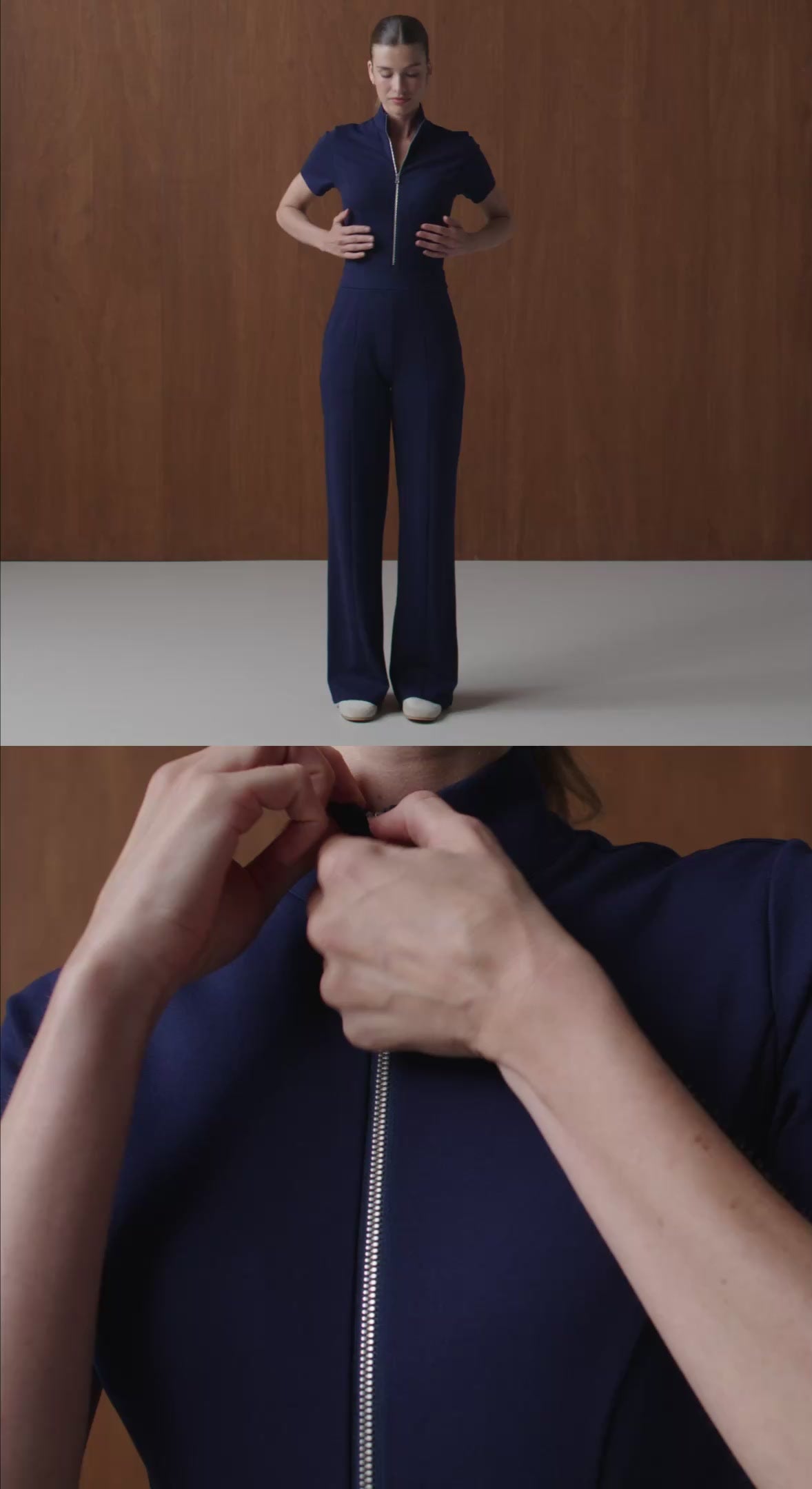 Stacked frame of a woman in a navy Jaanuu zip-front scrub top and wide-leg scrub pants standing against a wood-panel wall, above a close-up of her hands pulling the zipper up at the collar
