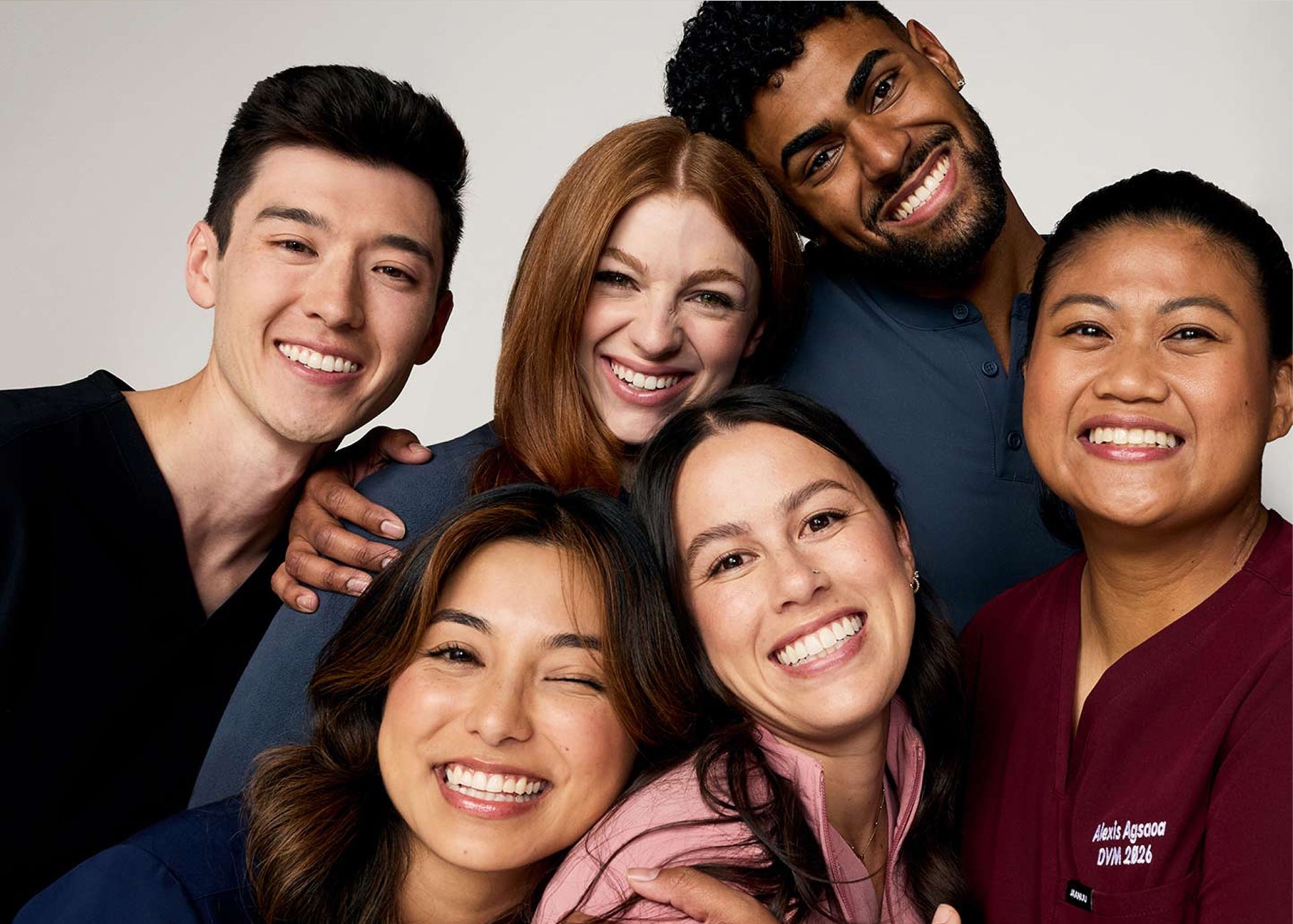 Six smiling healthcare workers in scrubs posing close together