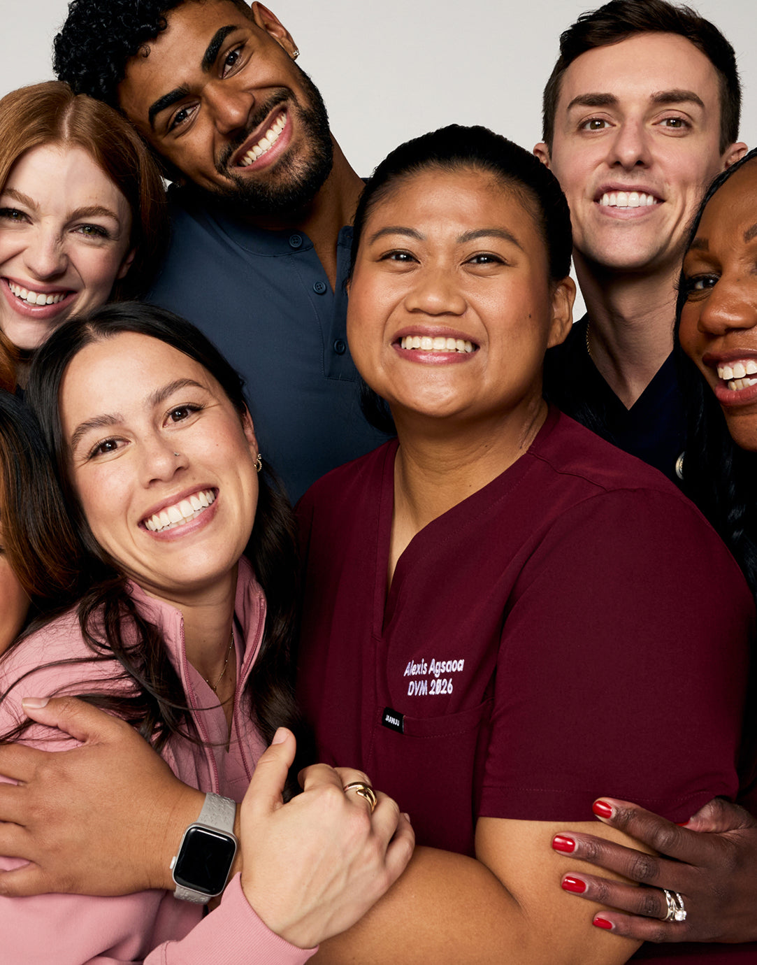 Six smiling healthcare workers in scrubs posing close together