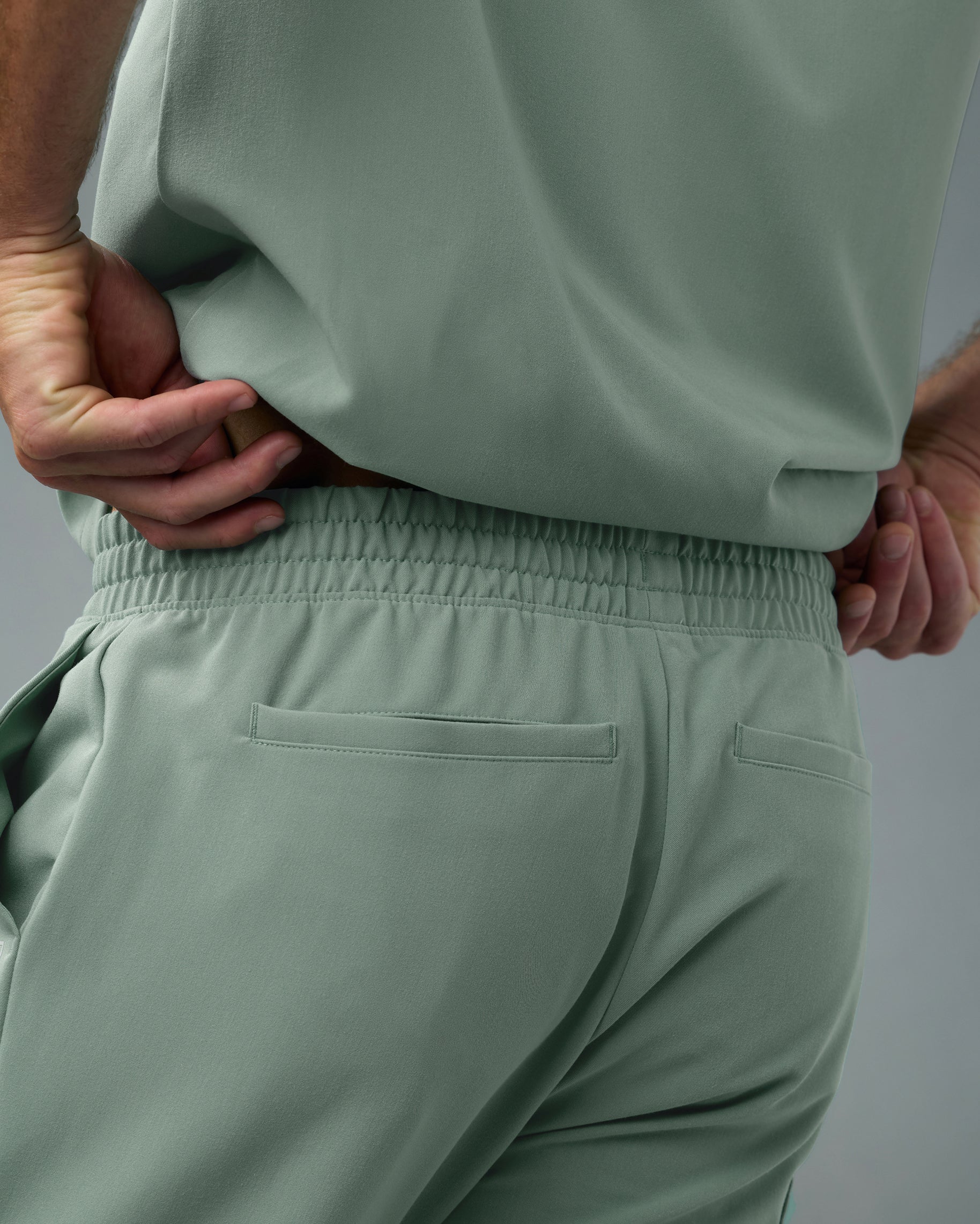 Back view of the elastic waistband and back welt pockets of sage green scrub pants
