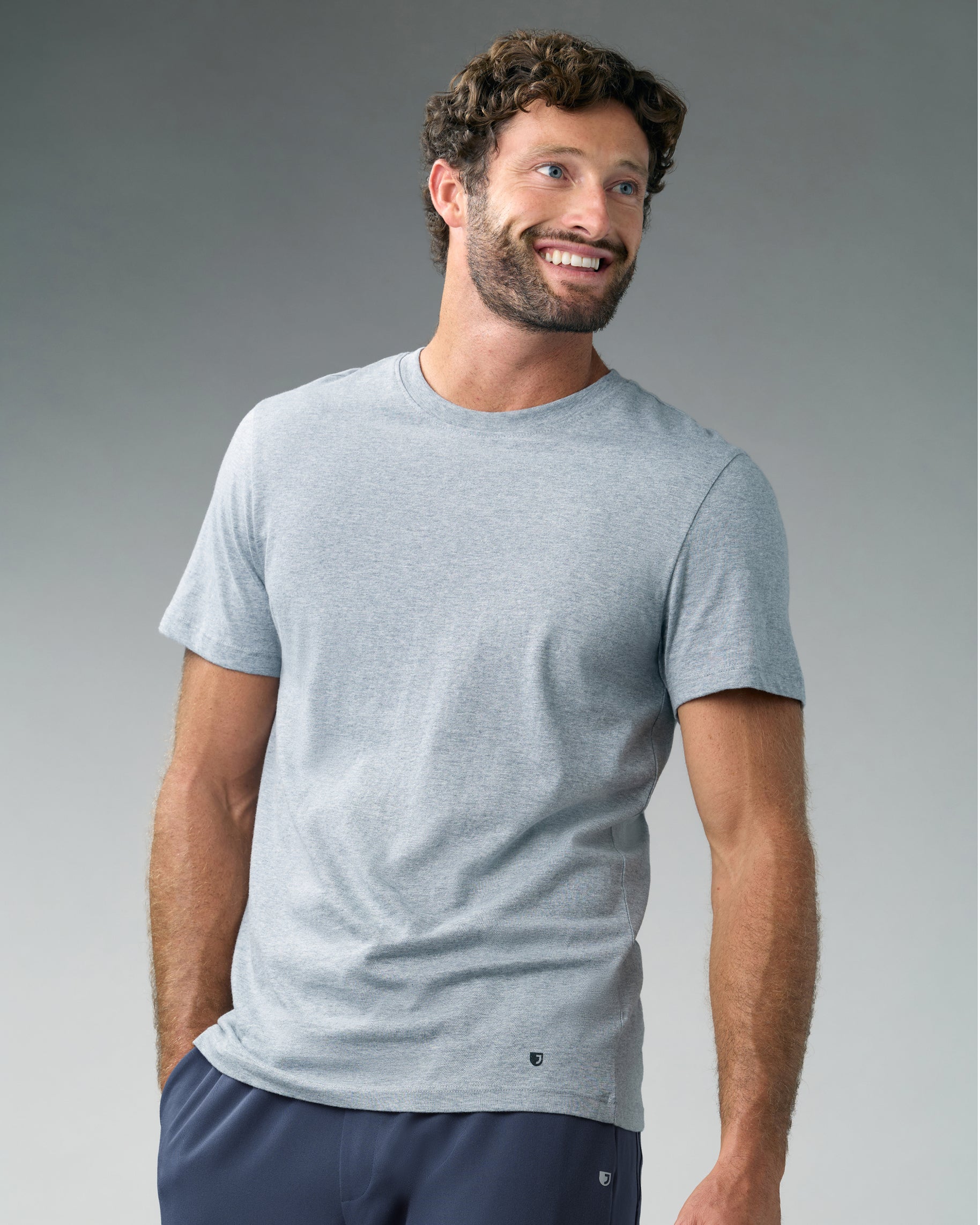 Smiling man in a heather gray short-sleeve crewneck underscrub and slate blue scrub pants