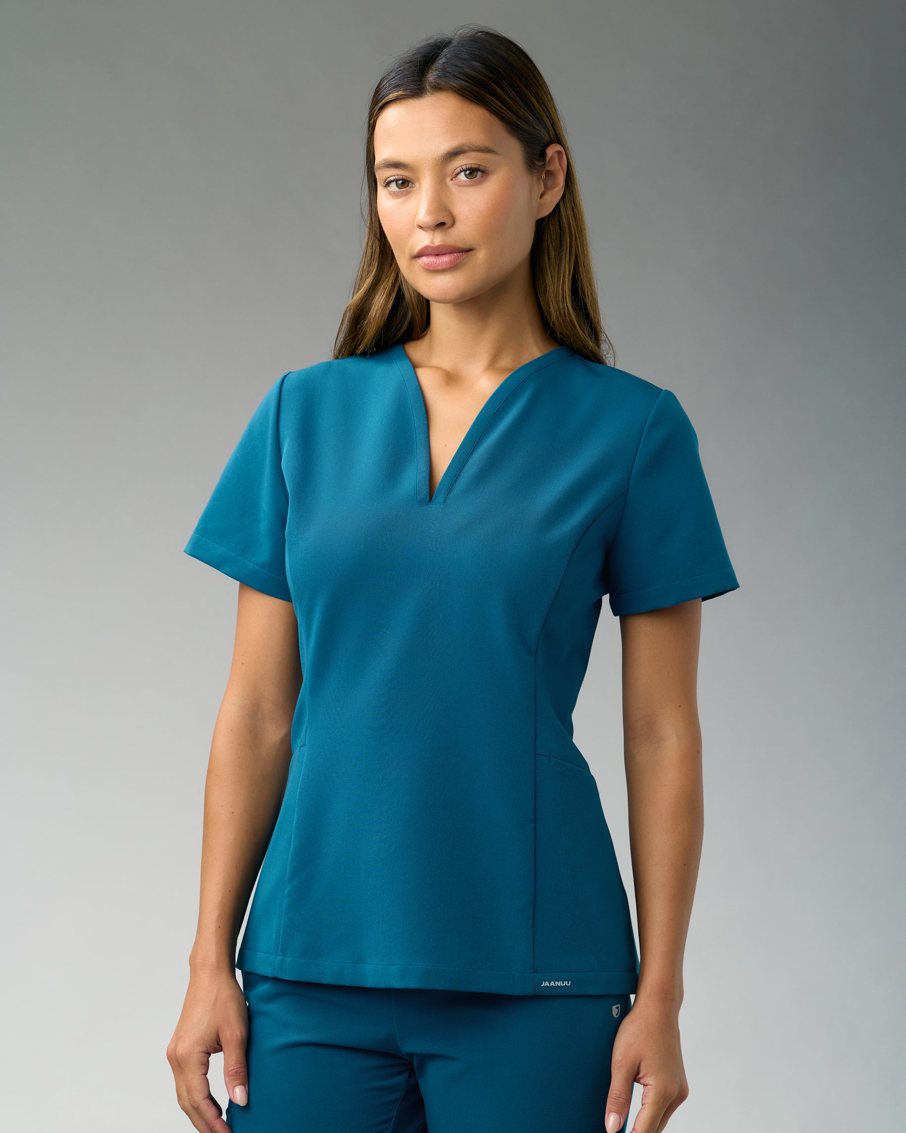 Woman in a fitted teal V-neck scrub top and matching scrub pants