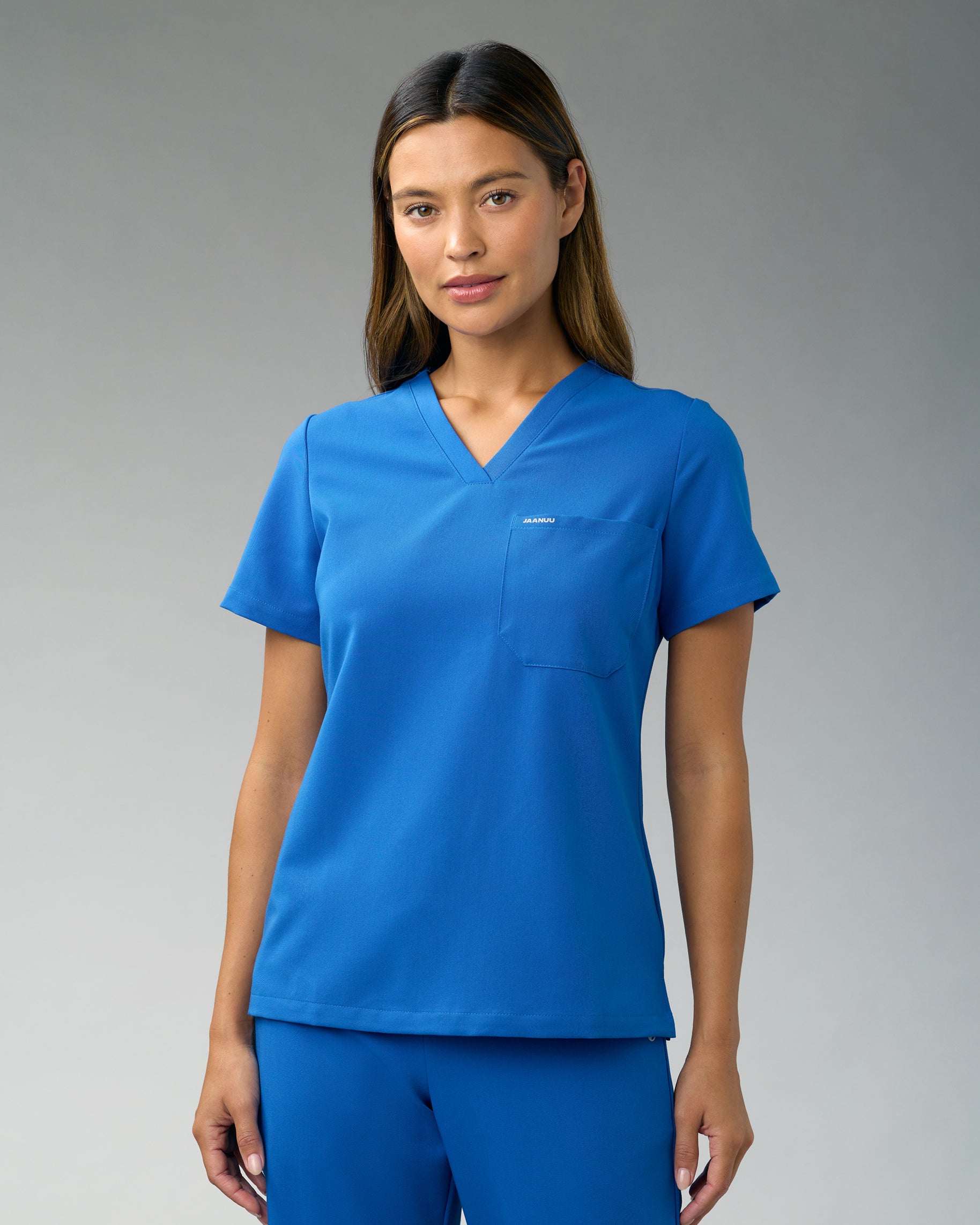 Woman in a royal blue slim V-neck scrub top with a chest pocket and matching scrub pants