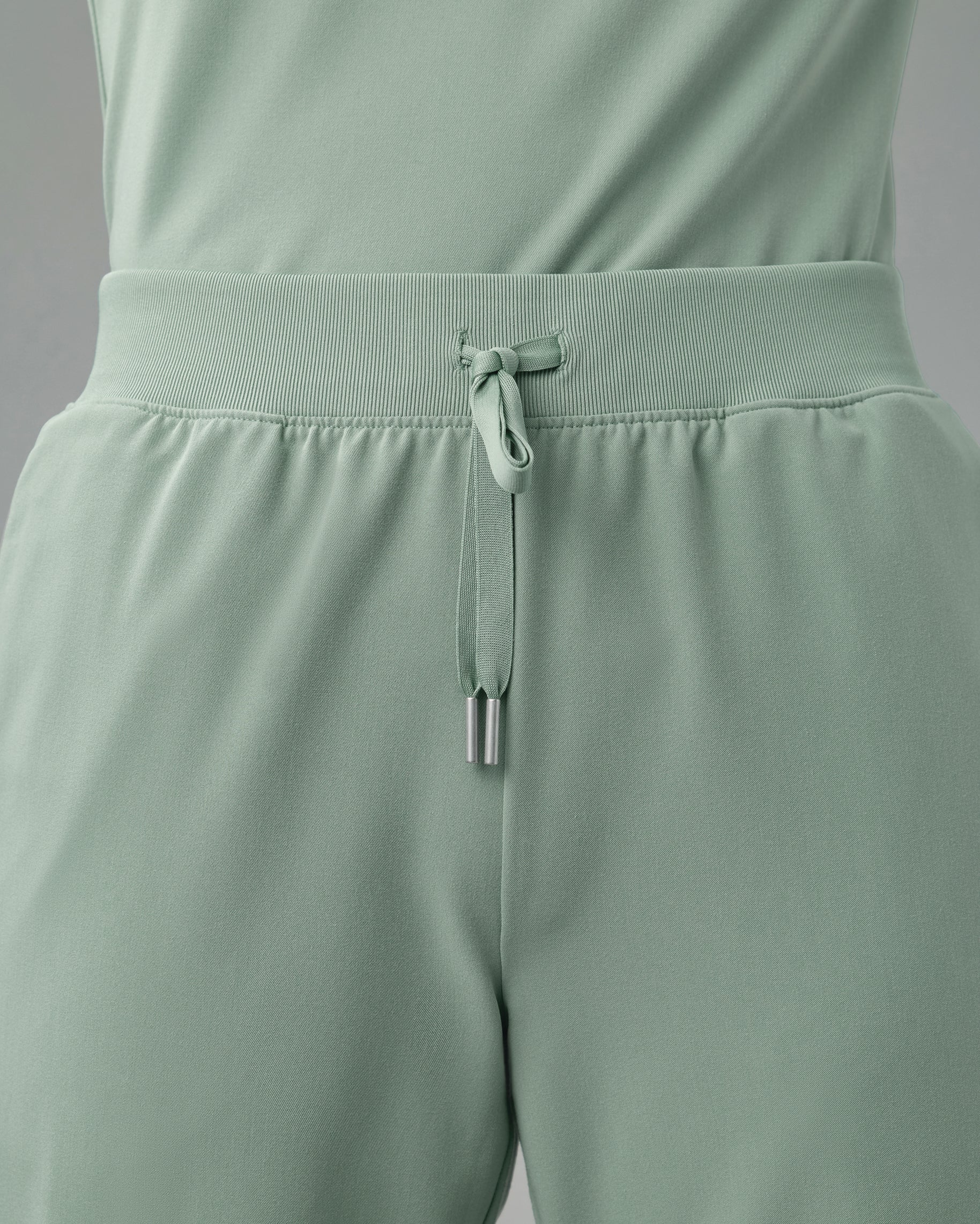Close-up of the rib-knit waistband and drawstring of sage green scrub pants