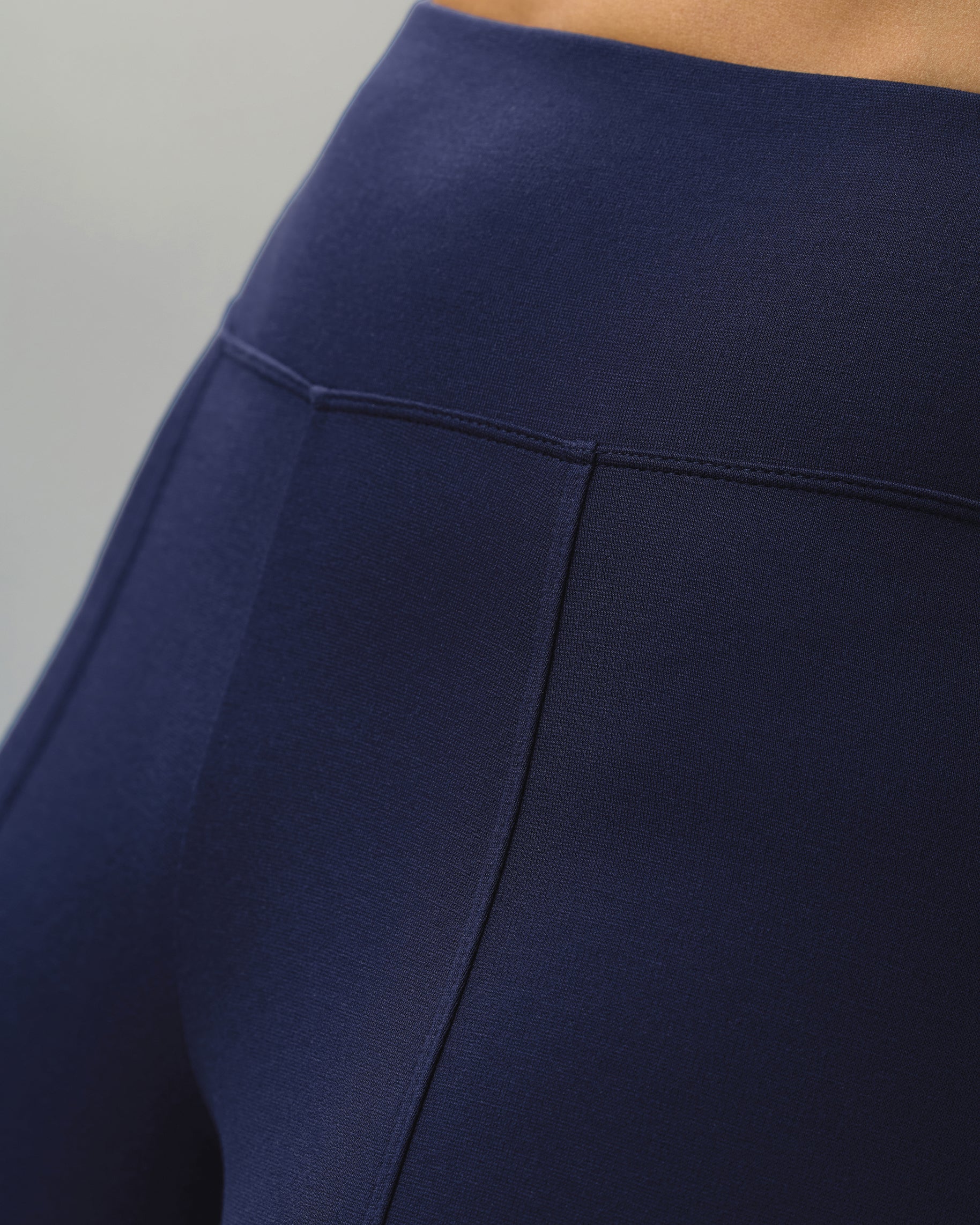 Close-up of the high-rise yoga waistband and front seam of navy scrub pants