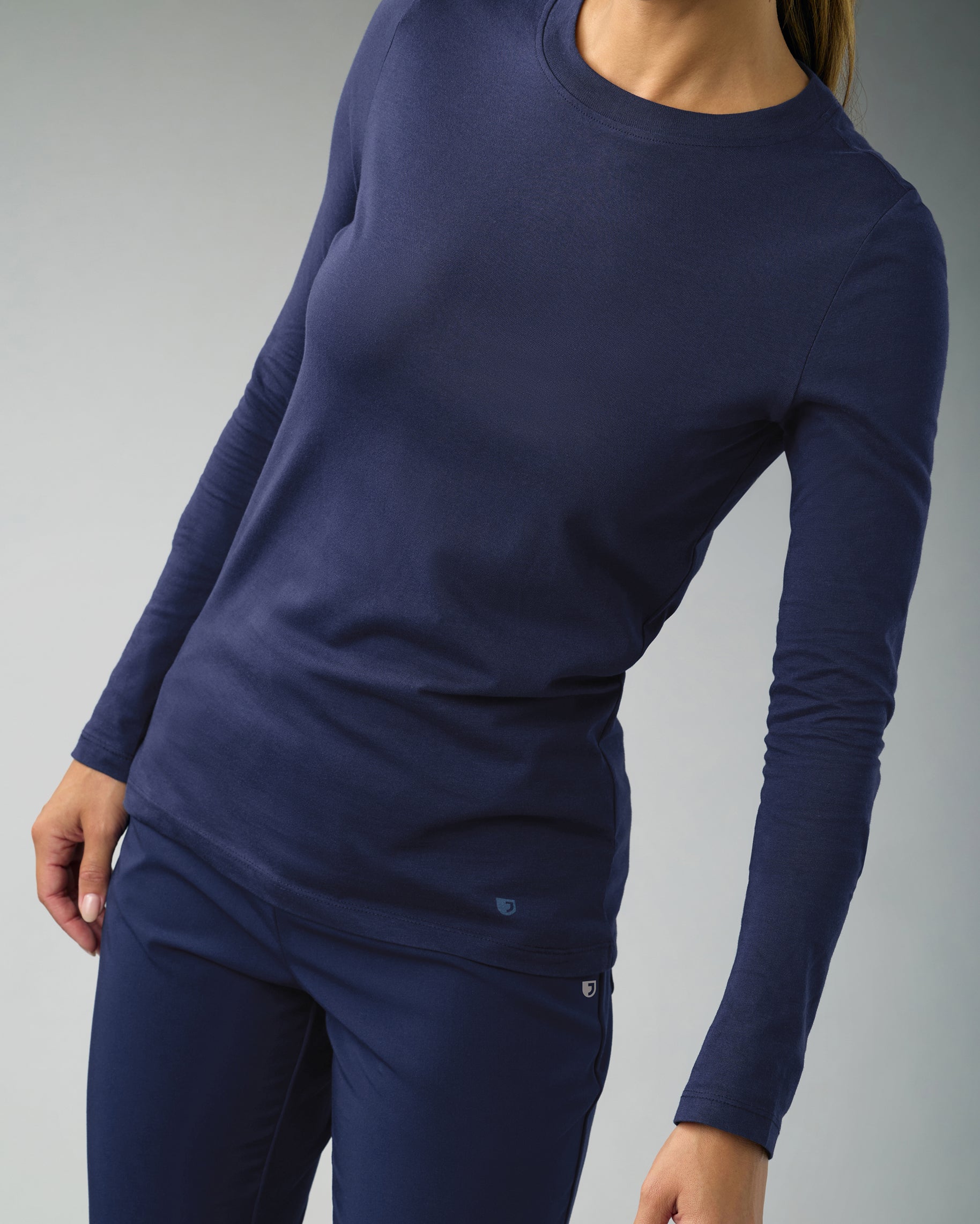 Woman in a navy long-sleeve crewneck underscrub and navy scrub pants