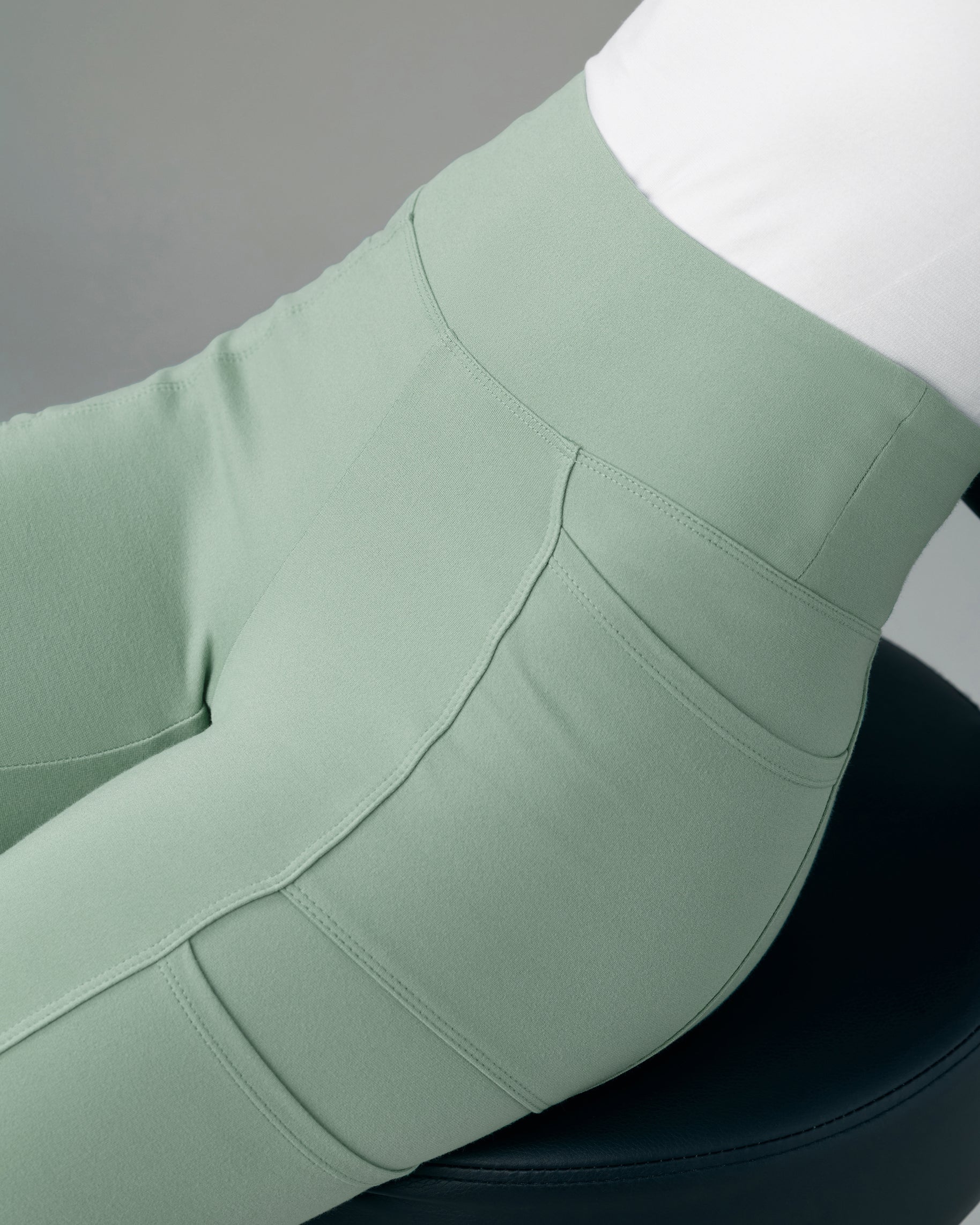 Close-up of the wide yoga waistband and seamed hip of sage green scrub pants